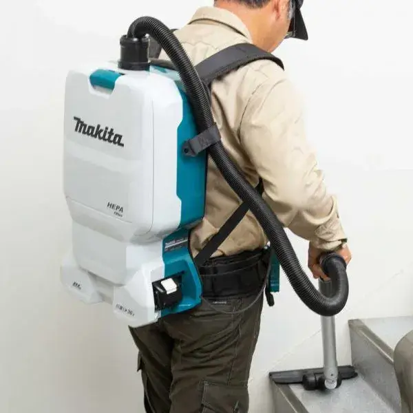 DVC660Z-MAKITA-18Vx2-Cordless-Backpack-Vacuum-Cleaner-1 Person wearing DVC660Z MAKITA 18Vx2 cordless backpack vacuum cleaner while cleaning indoor surfaces